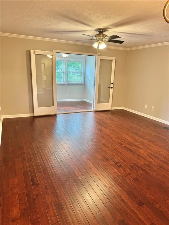 121 Brittany Ct, Duluth, GA 30096 - empty room with a textured ceiling, a ceiling fan, dark wood-type flooring, baseboards, and ornamental molding