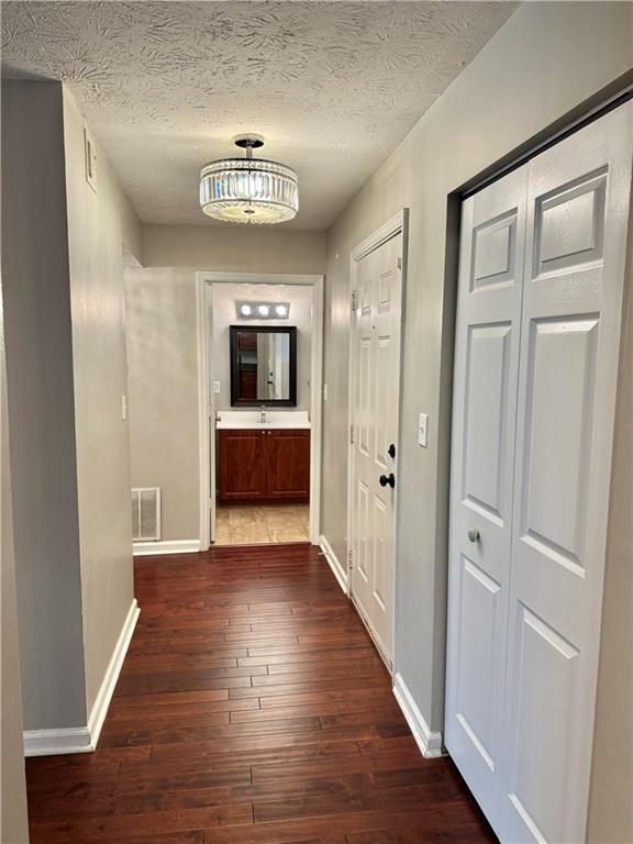 121 Brittany Ct, Duluth, GA 30096 - corridor with dark wood-style flooring, baseboards, and a textured ceiling