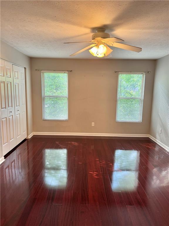121 Brittany Ct, Duluth, GA 30096 - unfurnished bedroom featuring baseboards, a textured ceiling, multiple windows, and hardwood / wood-style flooring