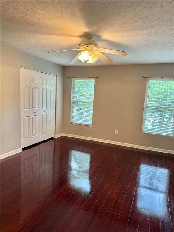 121 Brittany Ct, Duluth, GA 30096 - unfurnished bedroom featuring baseboards, multiple windows, dark wood-type flooring, and a textured ceiling