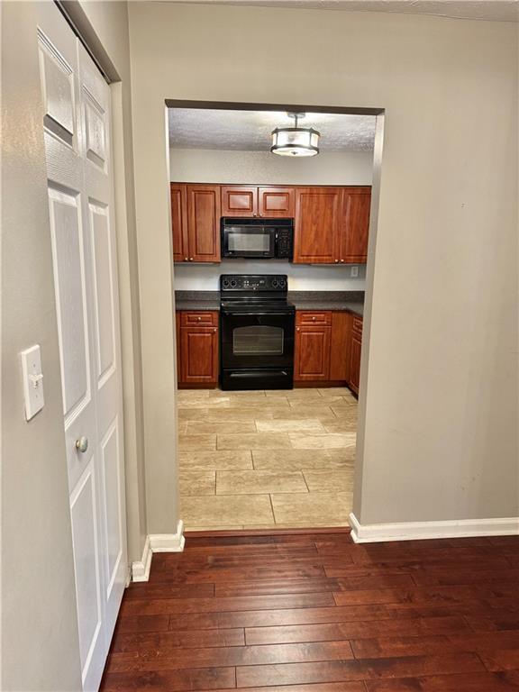 121 Brittany Ct, Duluth, GA 30096 - kitchen featuring black appliances, hardwood / wood-style flooring, dark countertops, and brown cabinets