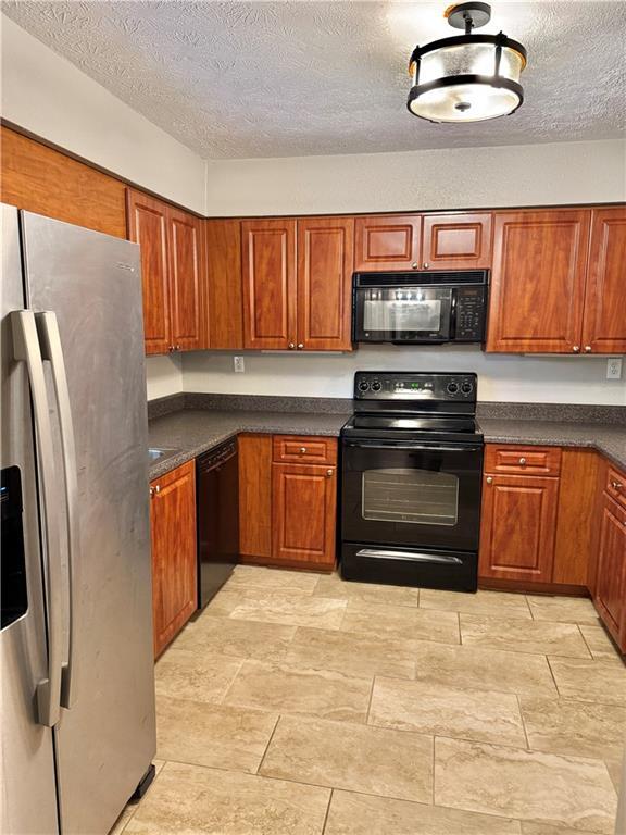 121 Brittany Ct, Duluth, GA 30096 - kitchen featuring black appliances, dark countertops, a textured ceiling, and brown cabinets