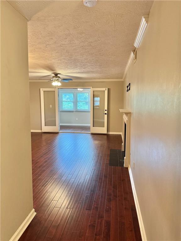 121 Brittany Ct, Duluth, GA 30096 - unfurnished living room with ceiling fan, dark wood finished floors, a fireplace with flush hearth, a textured ceiling, and baseboards