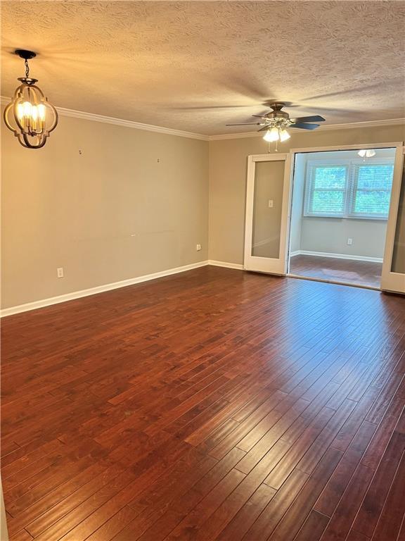 121 Brittany Ct, Duluth, GA 30096 - empty room featuring a chandelier, dark wood-style flooring, a textured ceiling, crown molding, and baseboards