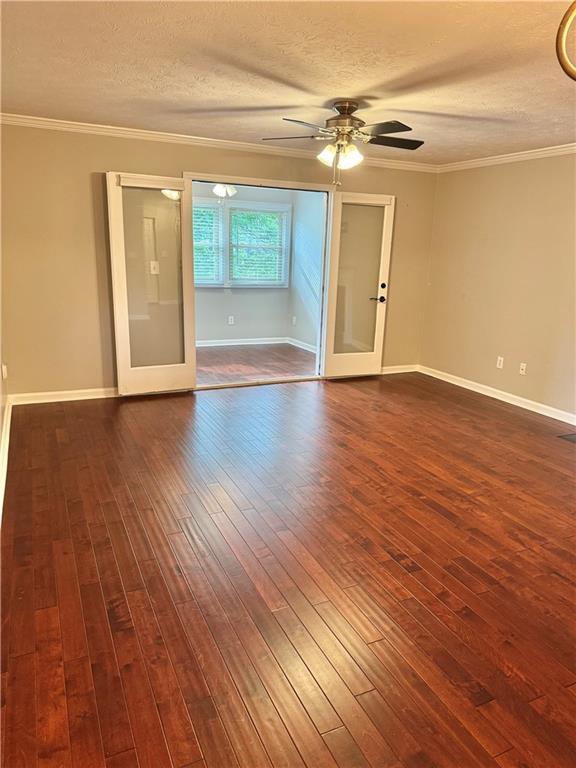 121 Brittany Ct, Duluth, GA 30096 - empty room featuring a textured ceiling, a ceiling fan, dark wood finished floors, baseboards, and crown molding