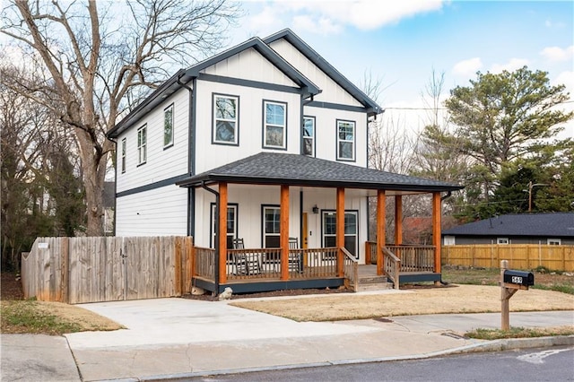 view of front of home with covered porch, fence, and a shingled roof