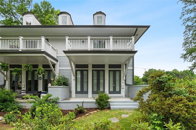 rear view of property featuring french doors, a porch, and a balcony
