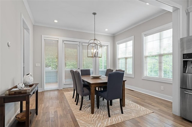dining area with crown molding, a chandelier, baseboards, and light wood finished floors