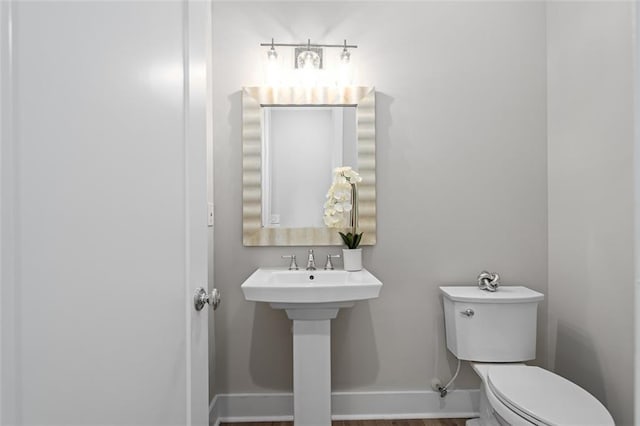 half bath featuring baseboards, toilet, and wood finished floors