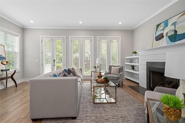 living area featuring crown molding, a fireplace with flush hearth, wood finished floors, recessed lighting, and baseboards