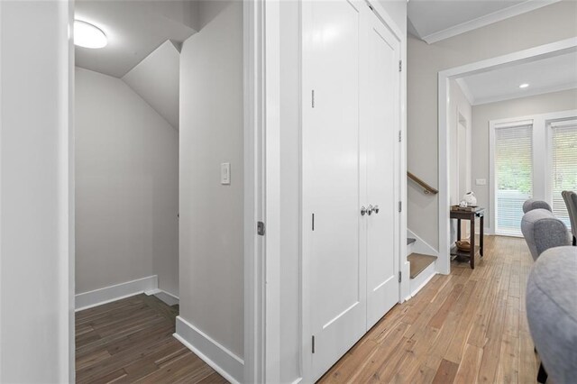 hall with light wood finished floors, ornamental molding, and baseboards