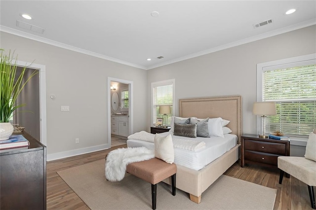 bedroom featuring baseboards, crown molding, wood finished floors, recessed lighting, and ensuite bath