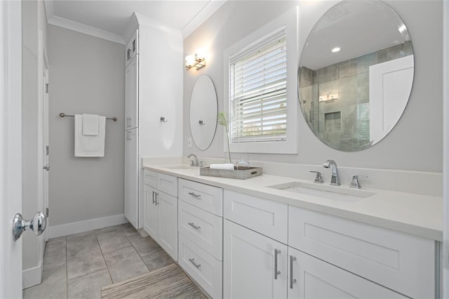 bathroom with a tile shower, ornamental molding, baseboards, and double vanity