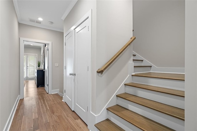 staircase featuring wood finished floors, crown molding, baseboards, and recessed lighting