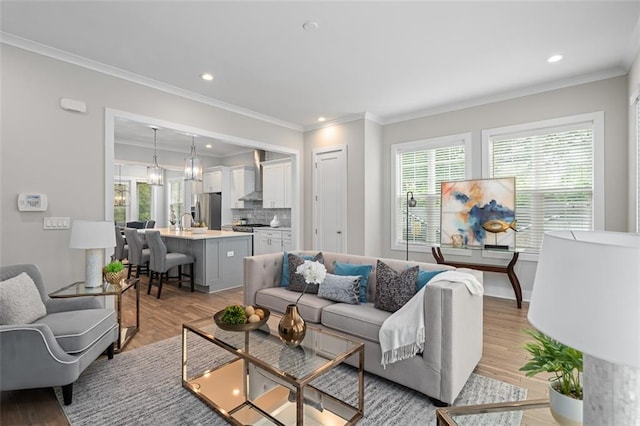 living room with ornamental molding, light wood-style flooring, and recessed lighting