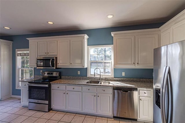 kitchen with light tile patterned floors, stainless steel appliances, white cabinetry, and sink