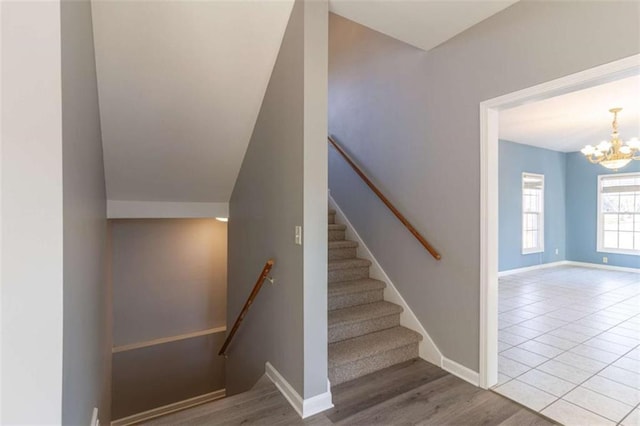 stairway with hardwood / wood-style flooring and an inviting chandelier