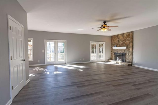 unfurnished living room with a fireplace, french doors, ceiling fan, and dark wood-type flooring