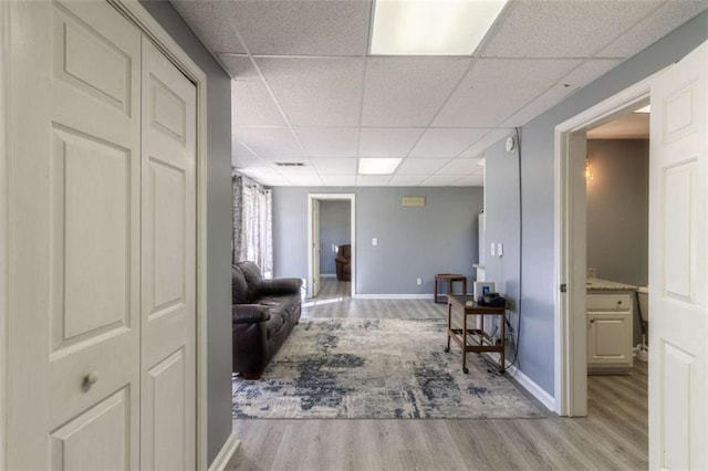 corridor featuring a paneled ceiling and light hardwood / wood-style flooring