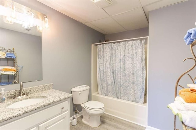 full bathroom featuring vanity, a drop ceiling, hardwood / wood-style flooring, toilet, and shower / bathtub combination with curtain