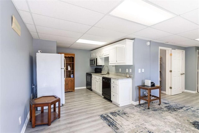 kitchen featuring white cabinetry, sink, light hardwood / wood-style flooring, a paneled ceiling, and black appliances