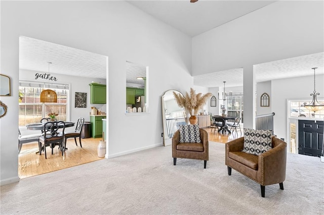 living area featuring a towering ceiling, light carpet, and a notable chandelier