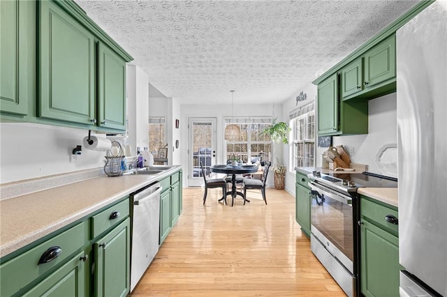 kitchen featuring stainless steel appliances, sink, light hardwood / wood-style floors, and green cabinetry