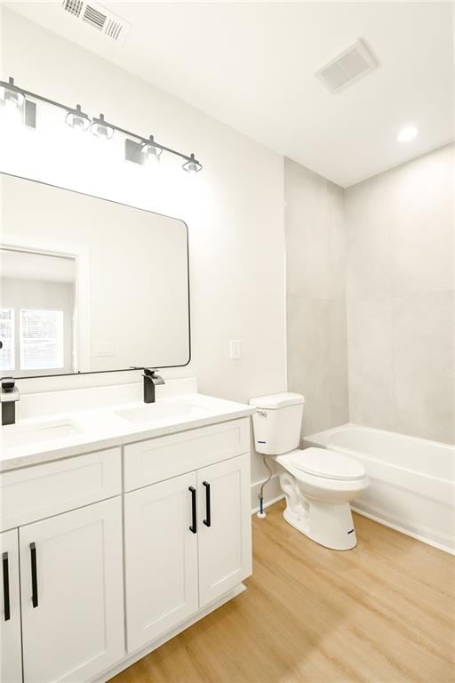 bathroom with toilet, wood finished floors, a sink, and visible vents