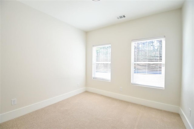 unfurnished room with visible vents, baseboards, and light colored carpet