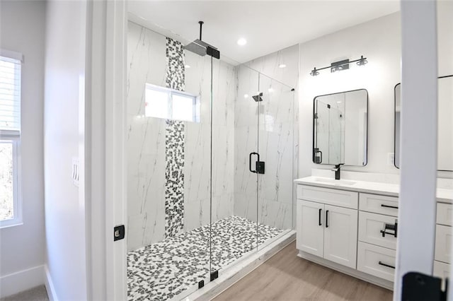 full bath with a marble finish shower, baseboards, wood finished floors, and vanity