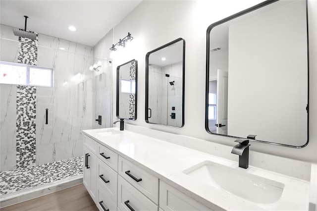 full bath featuring wood finished floors, a sink, and a marble finish shower