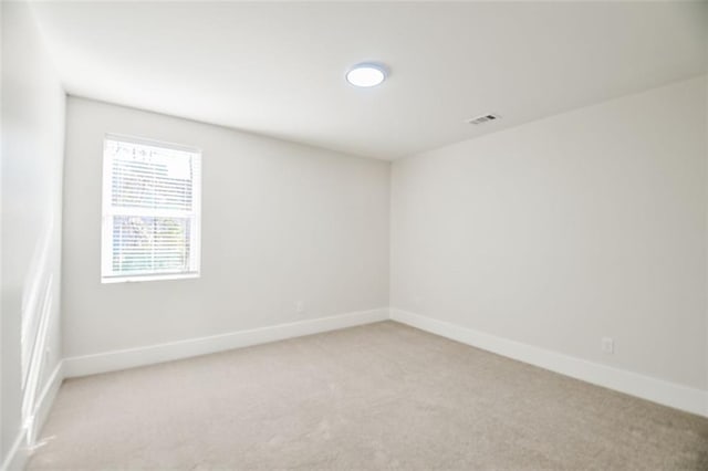 empty room with baseboards, visible vents, and light colored carpet