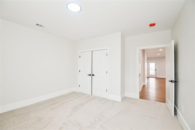 unfurnished bedroom featuring carpet floors, baseboards, visible vents, and a closet