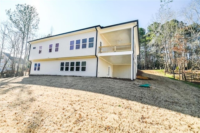 rear view of property featuring driveway, ceiling fan, and a balcony