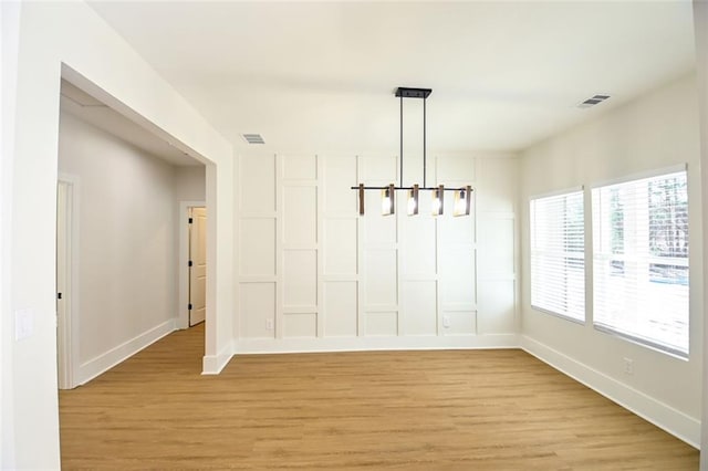 unfurnished dining area with light wood finished floors, visible vents, and baseboards