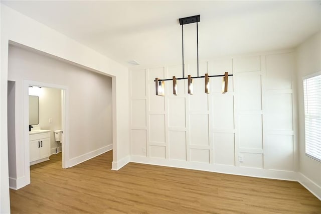 unfurnished dining area with light wood-style floors and baseboards