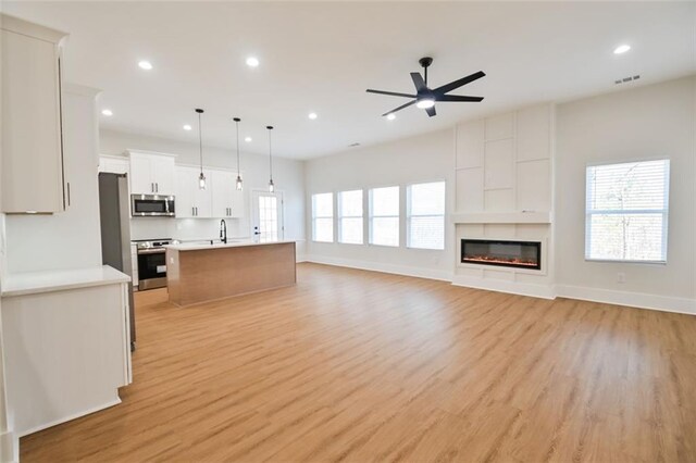 kitchen with open floor plan, stainless steel microwave, range, and visible vents