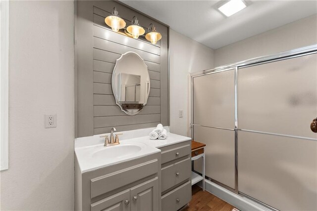 full bathroom with vanity, wood finished floors, and a shower stall