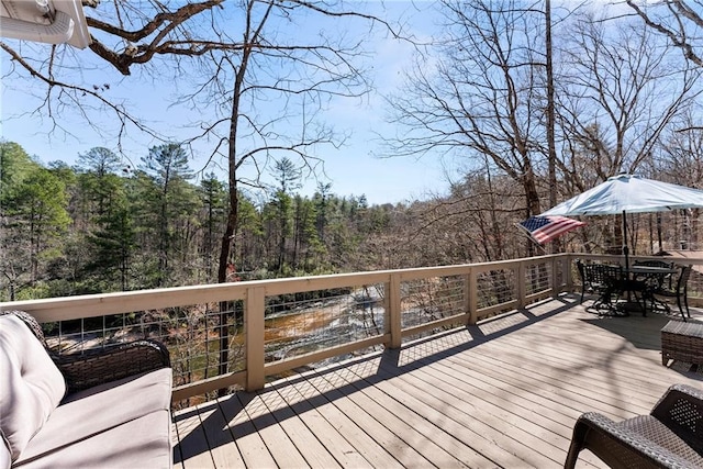 deck featuring a wooded view and outdoor dining space