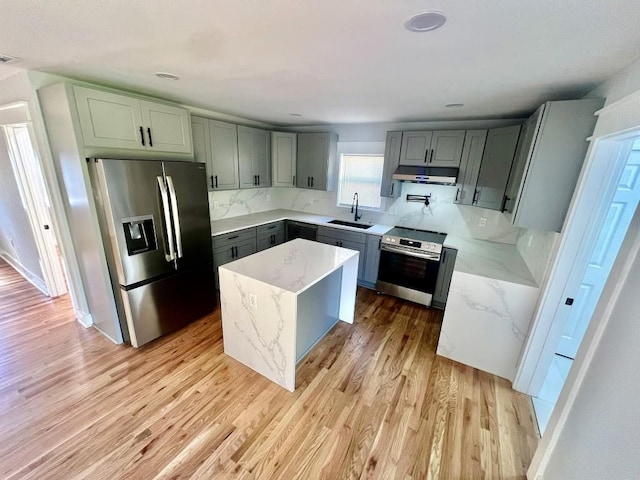 kitchen with light stone counters, a center island, sink, and stainless steel appliances