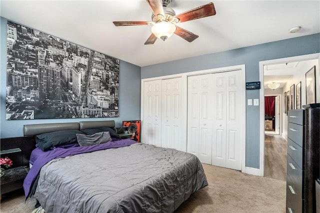 carpeted bedroom featuring baseboards, multiple closets, and ceiling fan