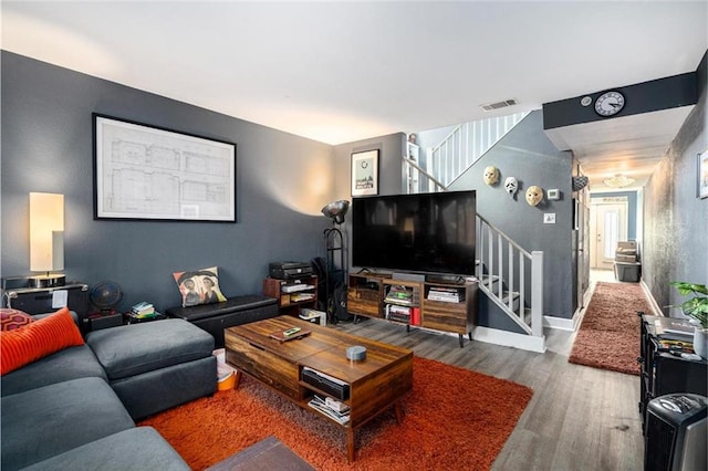living area featuring wood finished floors, baseboards, stairway, and visible vents