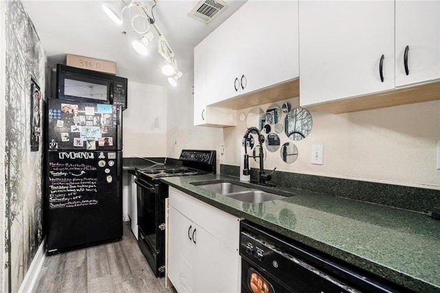 kitchen with white cabinetry, black appliances, a sink, and dark stone counters