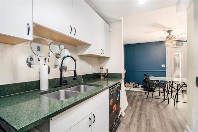 kitchen featuring white cabinets, ceiling fan, black dishwasher, a sink, and light wood-style floors