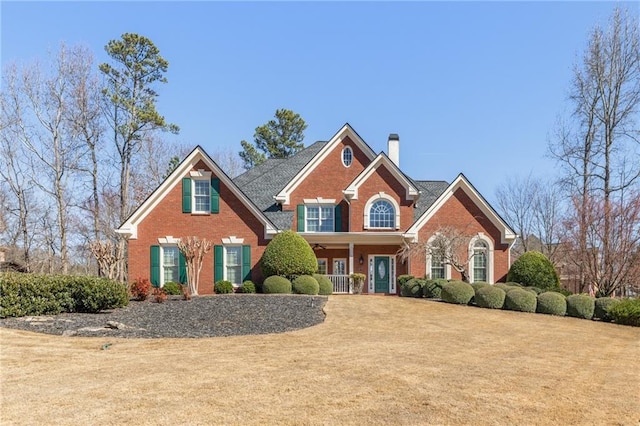 view of front facade featuring brick siding, a chimney, and a front lawn