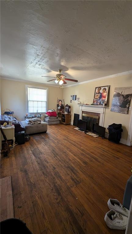 living room with a textured ceiling, ceiling fan, hardwood / wood-style floors, and a brick fireplace