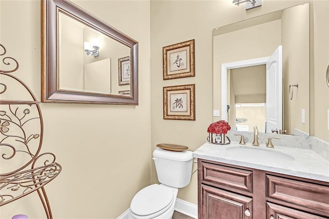 half bath featuring vanity, toilet, and baseboards