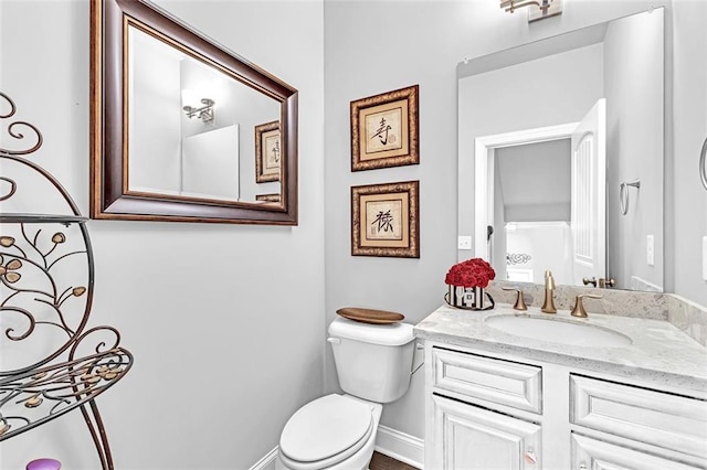 bathroom with baseboards, vanity, and toilet