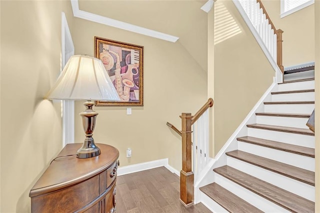 stairway with crown molding, baseboards, and wood finished floors