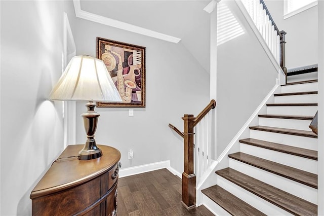 stairway with crown molding, vaulted ceiling, wood finished floors, and baseboards